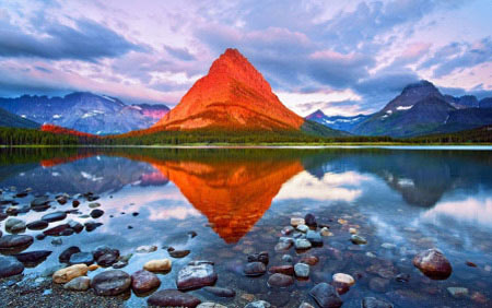 Bức ảnh trông giống như một sự kết hợp giữa một hồ nước trên núi và một ngọn núi trên sao Hỏa. Nhưng nó thực sự chỉ là ánh nắng mặt trời buổi hoàng hôn chiếu qua những đám mây ở Vườn quốc gia Glacier thuộc Montana.
